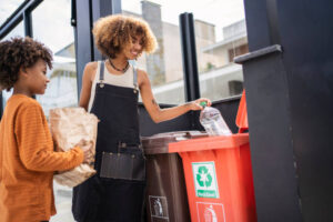 Young woman and her younger brother recycling garbage at home.