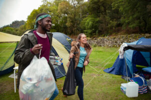 A couple are carrying rubbish bags after camping.
